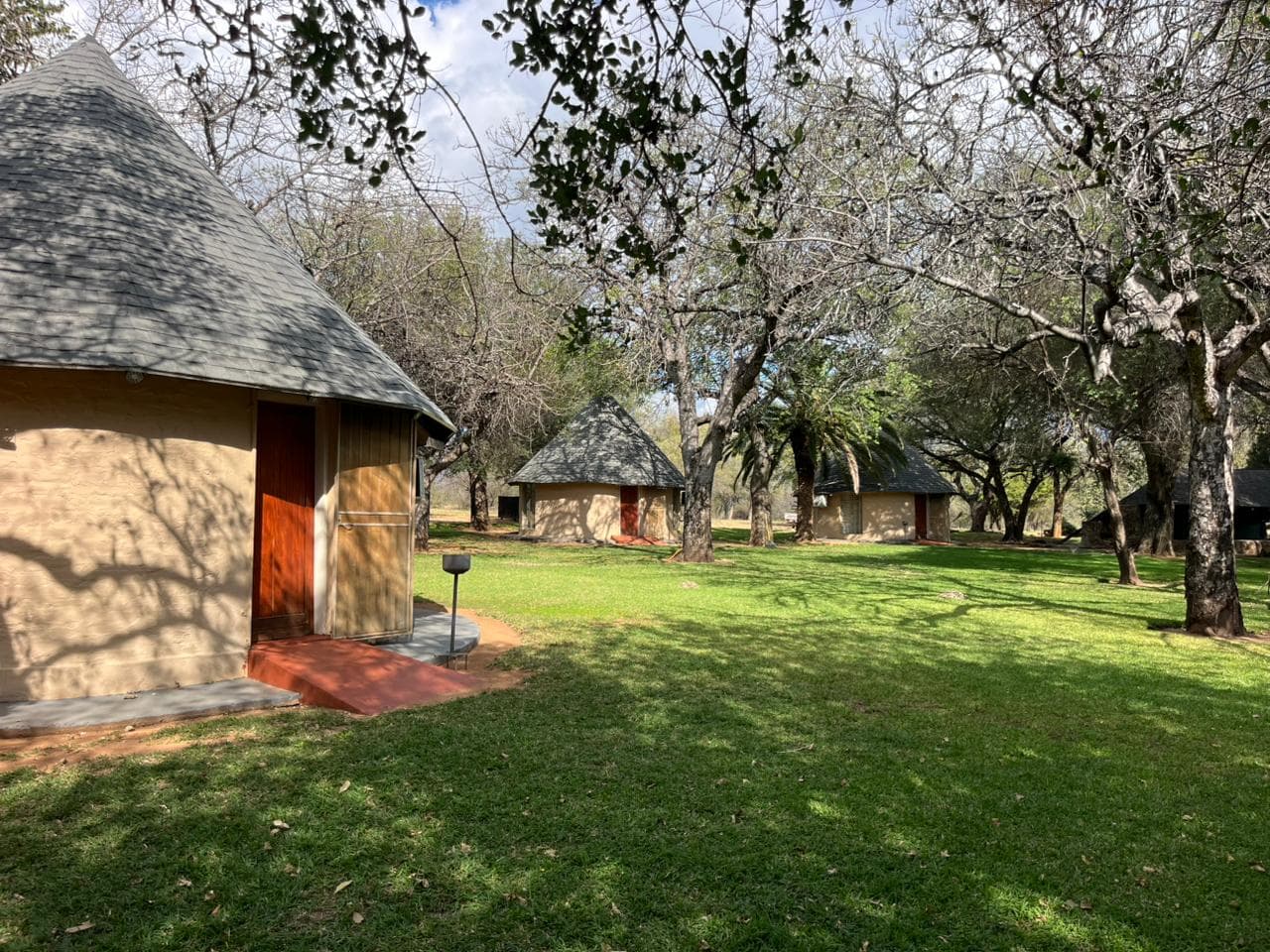 Camp grounds with thatched buildings and trees